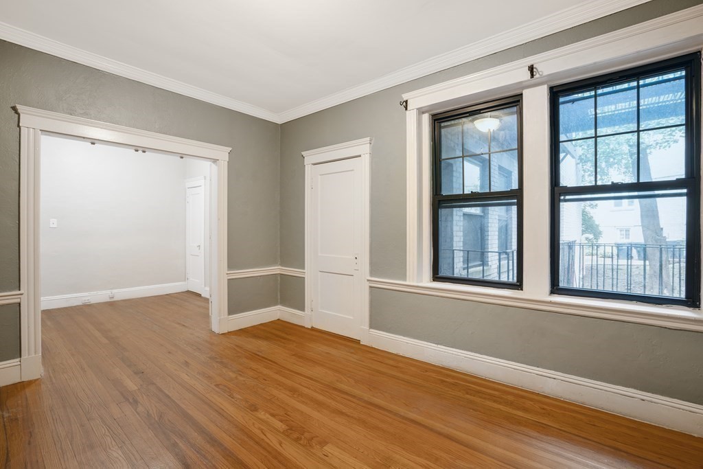 59 Lanark Road, Unit 2 Boston, MA 02135 - Photo 4 of 18 an empty room with wooden floor and windows