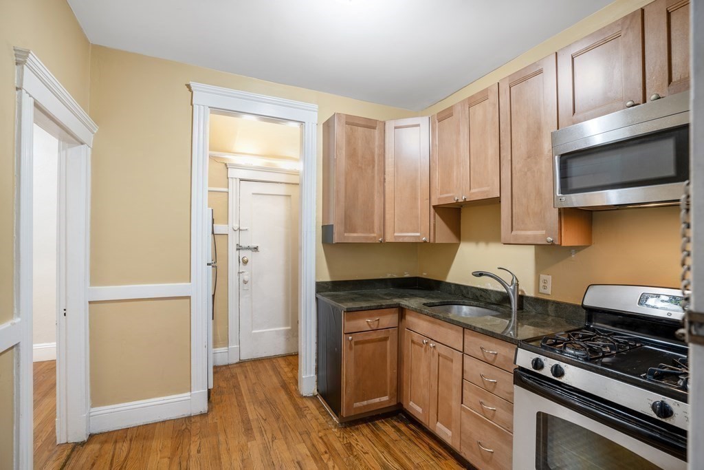 59 Lanark Road, Unit 2 Boston, MA 02135 - Photo 7 of 18 a kitchen with granite countertop wooden cabinets and a stove top oven