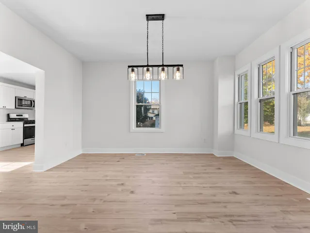 a view of an empty room with window and hardwood floor