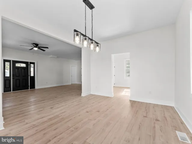 a view of an empty room with wooden floor ceiling fan
