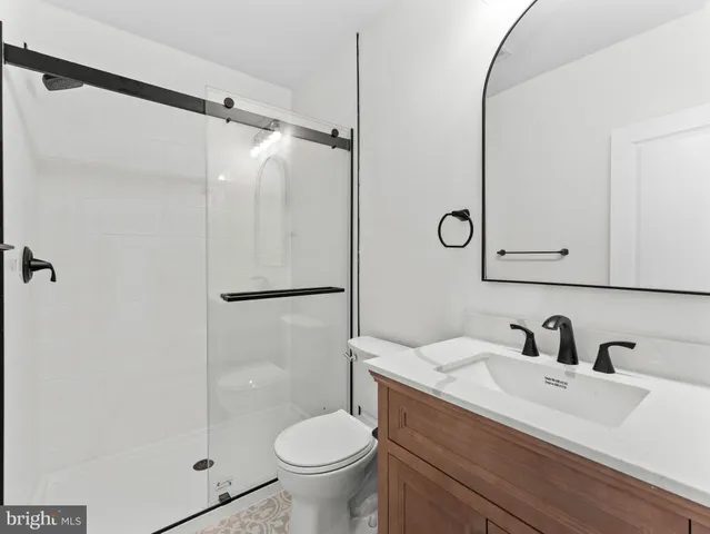 a bathroom with a shower sink vanity mirror and toilet