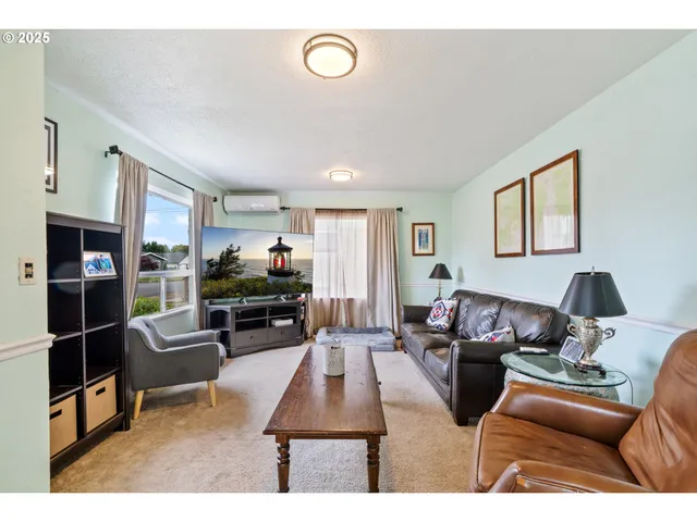 a living room with furniture a flat screen tv and a refrigerator