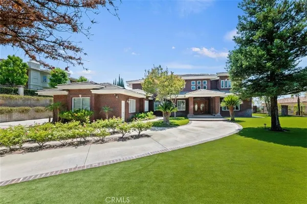 a front view of a house with a yard and a large tree