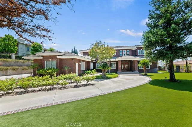 a front view of a house with a yard and a large tree