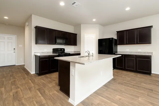 a kitchen with kitchen island stainless steel appliances a sink cabinets and a counter top space