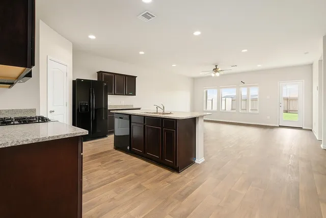 a kitchen with stainless steel appliances granite countertop a refrigerator a sink dishwasher and a oven with wooden floor