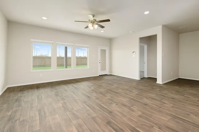 a view of an empty room with a window and wooden floor