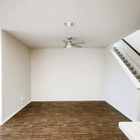 a view of a room with wooden floor and a ceiling fan