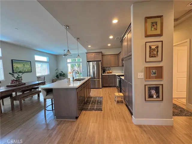 a living room with stainless steel appliances furniture wooden floor and a kitchen view