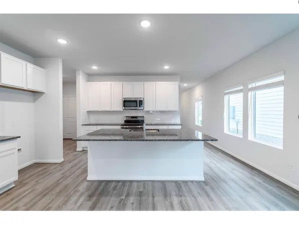 a kitchen with stainless steel appliances granite countertop a refrigerator a sink dishwasher a stove and white countertops with wooden floor