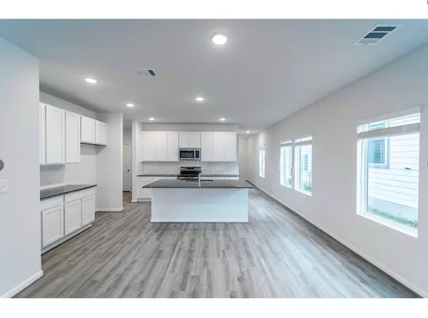 a open kitchen with kitchen island a sink dishwasher stove and white cabinets with wooden floor
