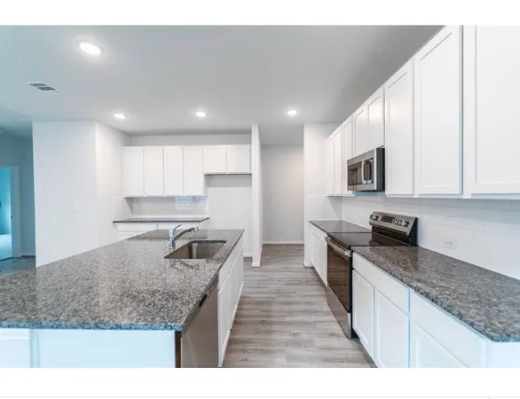 a kitchen with stainless steel appliances granite countertop a sink stove and microwave