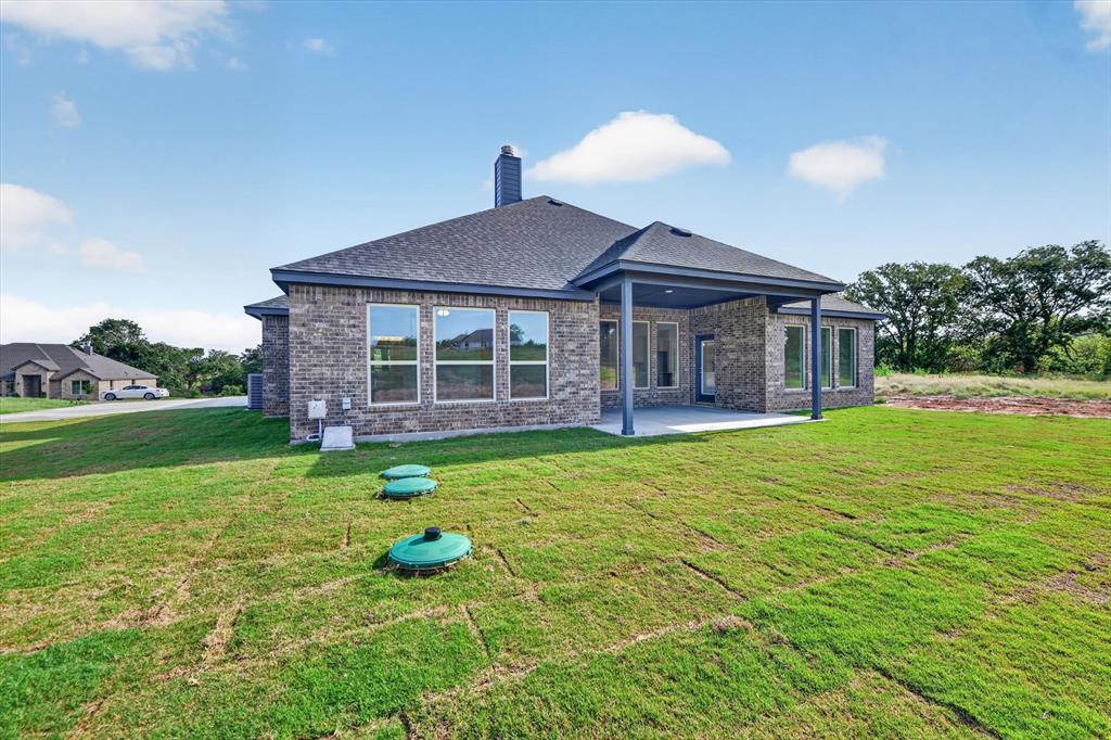 416 McAlpine Drive Springtown, TX 76082 - Photo 34 of 40 Rear exterior featuring a covered patio, brick facade, and a dark shingle roof