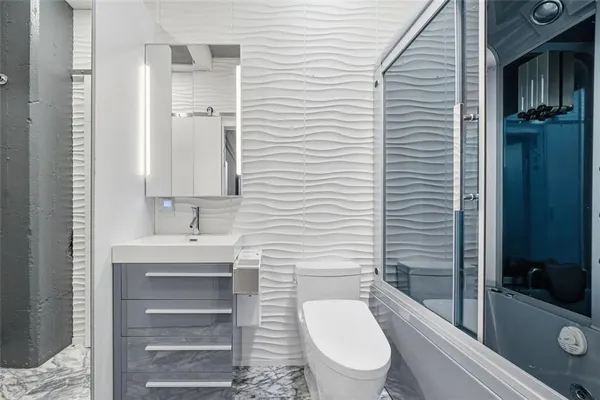 a view of a hallway with wooden floor and a bathroom