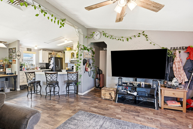 4296 Maple Lane Cedar City, UT 84721 - Photo 7 of 44 Open-concept living area featuring wood-finish flooring, a ceiling fan with light fixture, and a kitchen island with seating for three