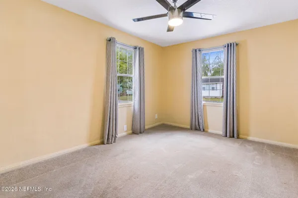 an empty room with windows and fan
