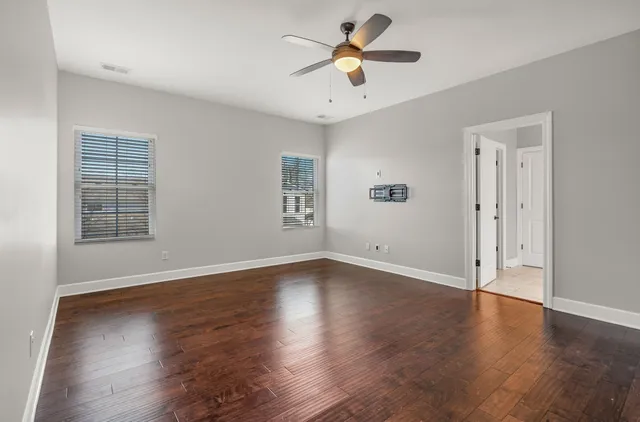 an empty room with wooden floor and windows