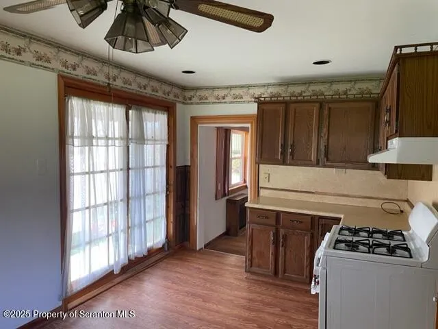 a kitchen with a stove a refrigerator and wooden floor