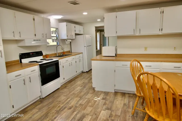 a kitchen with granite countertop a sink a stove and cabinets