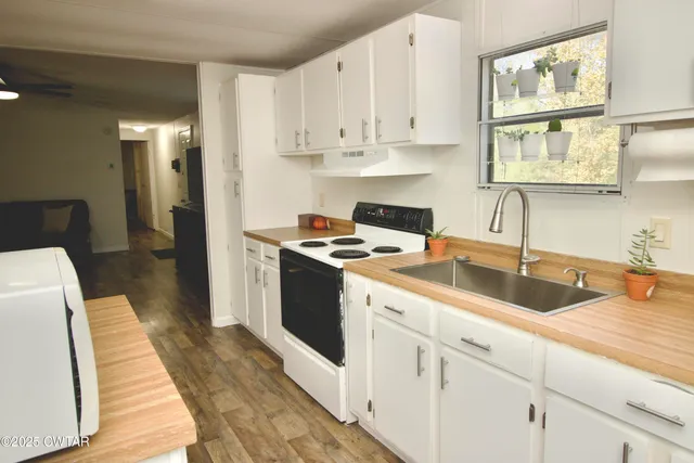 a kitchen with stainless steel appliances granite countertop a stove a sink and white cabinets