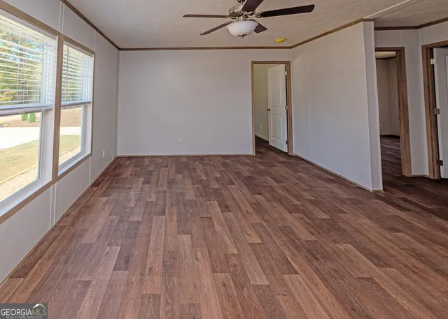a view of empty room with wooden floor and fan