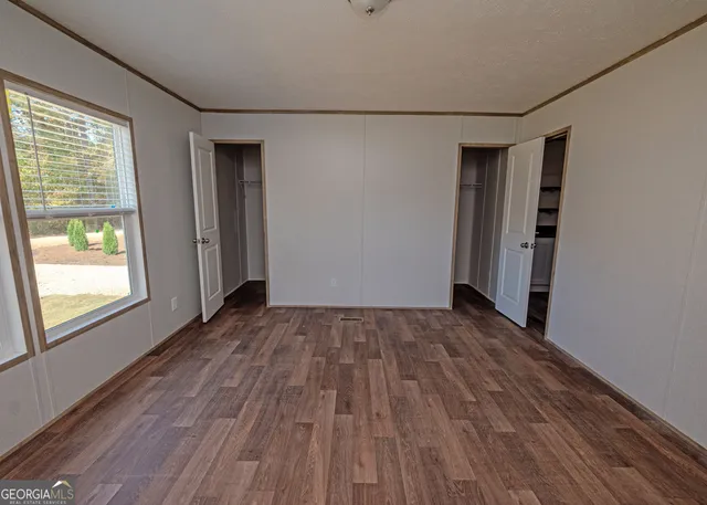 a view of empty room with wooden floor and fan
