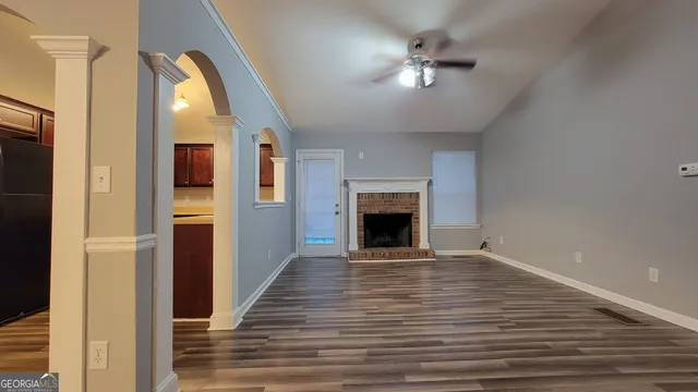 a view of an empty room with chandelier fan and fire place