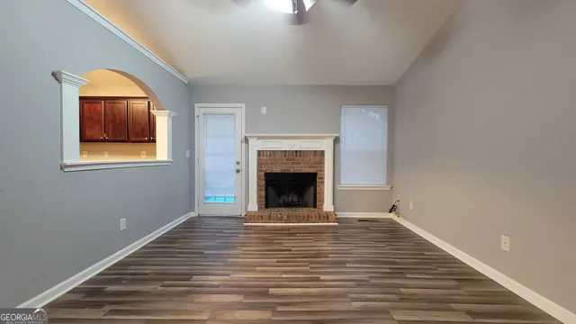 a view of an empty room with wooden floor fireplace and a window
