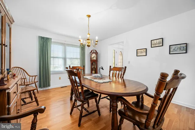 a view of kitchen with stainless steel appliances granite countertop dining table chairs sink and cabinets