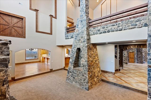 246 Woods Creek Road Morgan, UT 84050 - Photo 20 of 69 Two-story stone fireplace, vaulted ceilings, upper-level wood railing, wood-finish flooring, and arched doorways
