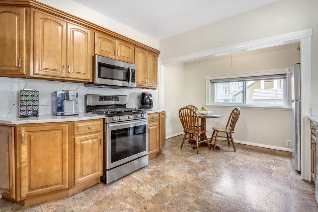 24 Baker Road Everett, MA 02149 - Photo 10 of 26 a kitchen with stainless steel appliances granite countertop a stove top oven a sink dishwasher a dining table and chairs with wooden floor