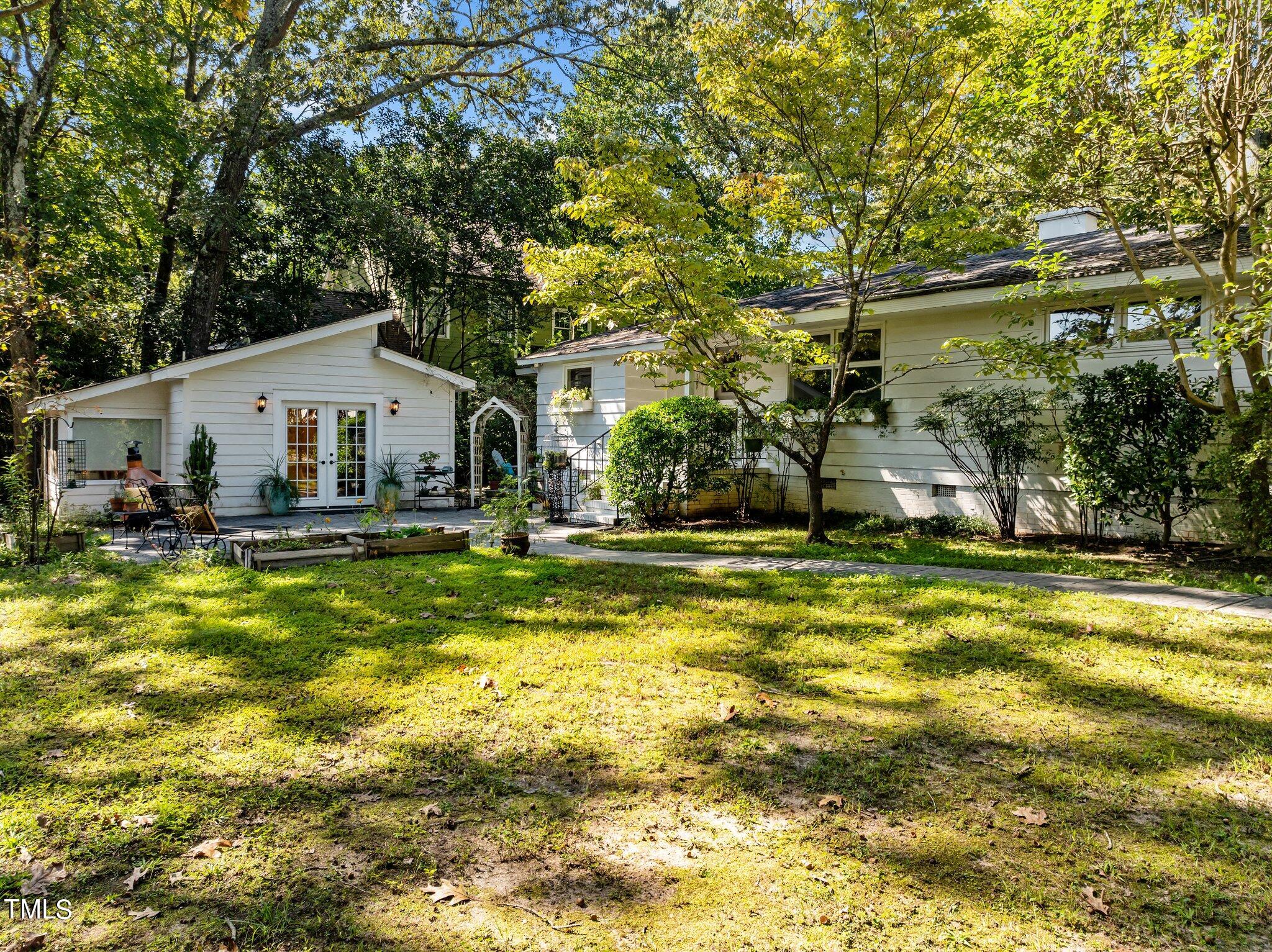 1510 Ridge Road Raleigh, NC 27607 - Photo 6 of 55 a view of a white house with a large pool and lawn chairs under an umbrella