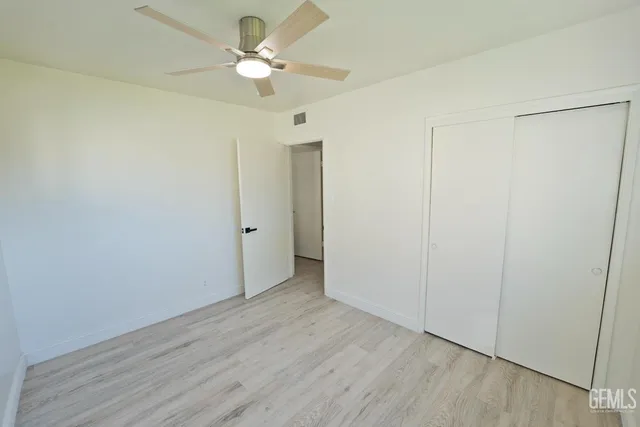 an empty room with wooden floor fan and windows