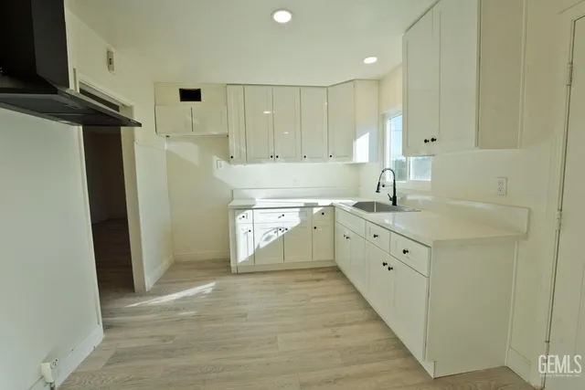 a large kitchen with a sink a refrigerator and window