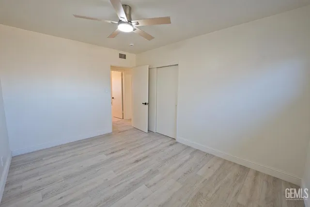an empty room with wooden floor fan and windows