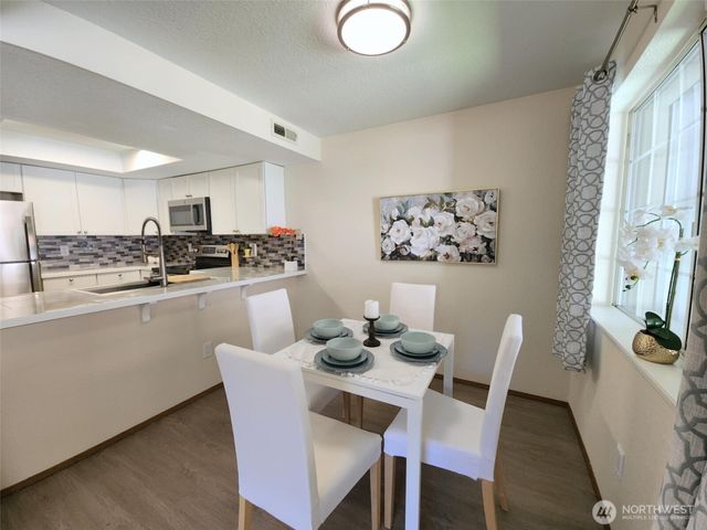 a kitchen with stainless steel appliances granite countertop a dining table chairs and a refrigerator