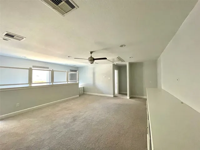 an empty room with windows and chandelier fan