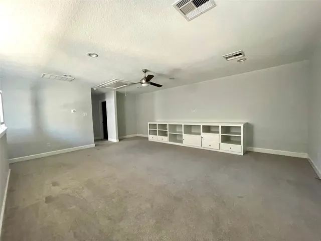 an empty room with windows and ceiling fan