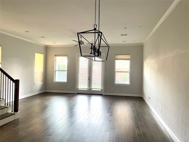 a view of an empty room with wooden floor fridge and a window