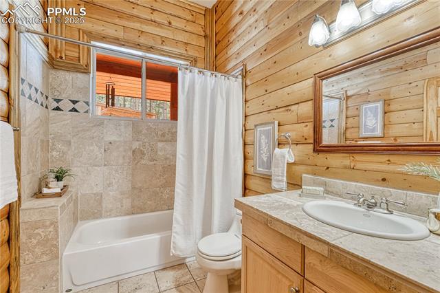 15975 Winding Trail Road Colorado Springs, CO 80908 - Photo 22 of 50 Full bathroom with travertine tile counters and shower/tub surround across from the bedroom