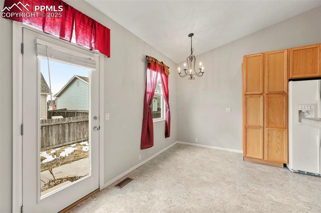 11927 Rodez Grove Peyton, CO 80831 - Photo 10 of 34 Unfurnished dining area with lofted ceiling, a healthy amount of sunlight, visible vents, and baseboards