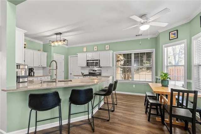 a kitchen with stainless steel appliances granite countertop table chairs stove and cabinets