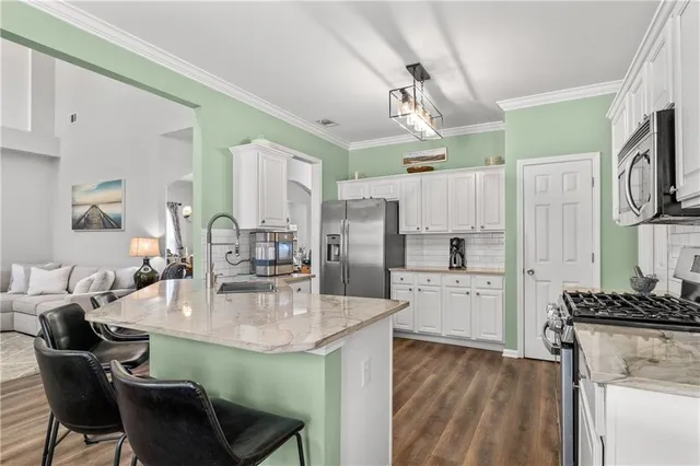 a kitchen with kitchen island a dining table chairs stainless steel appliances and cabinets