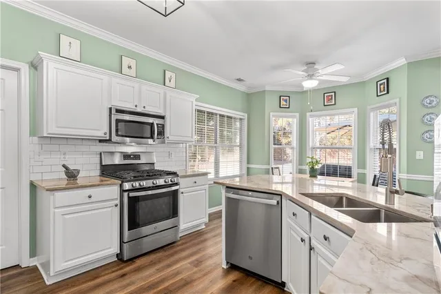 a kitchen with stainless steel appliances granite countertop a sink and cabinets with wooden floors