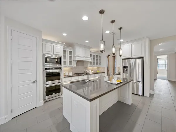 a kitchen with stainless steel appliances granite countertop a refrigerator a stove and a sink
