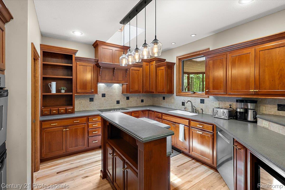 9867 Rainbow Ridge Drive Schoolcraft, MI 49087 - Photo 23 of 82 Well-appointed kitchen featuring extensive wood cabinetry, dark countertops, an integrated sink, stainless steel appliances, and a tiled backsplash