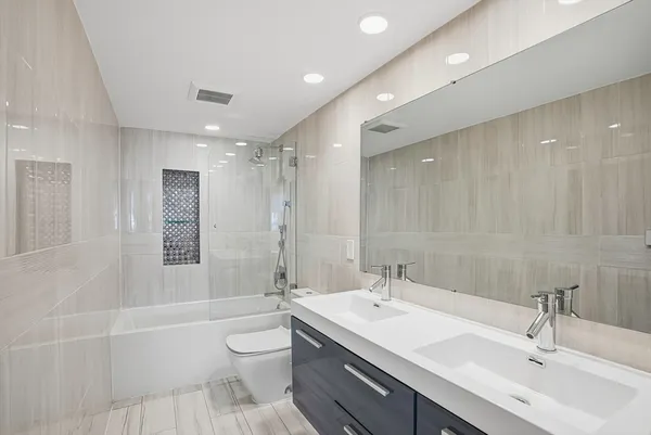 a bathroom with a double vanity sink toilet mirror and shower