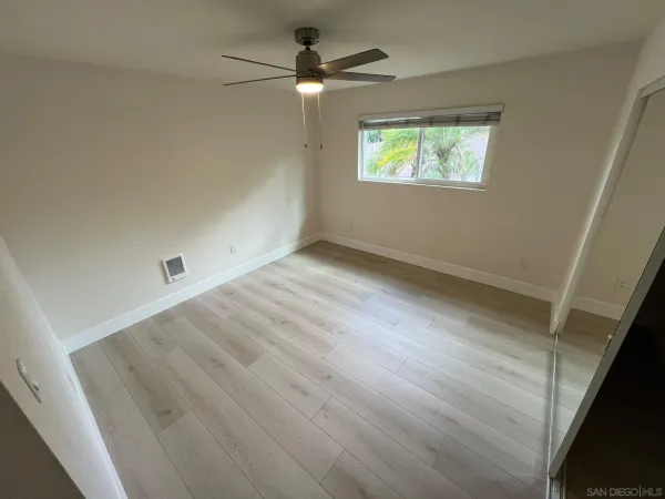 an empty room with windows and fan