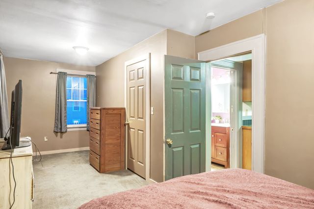 a bedroom with a bed dresser and a flat tv screen