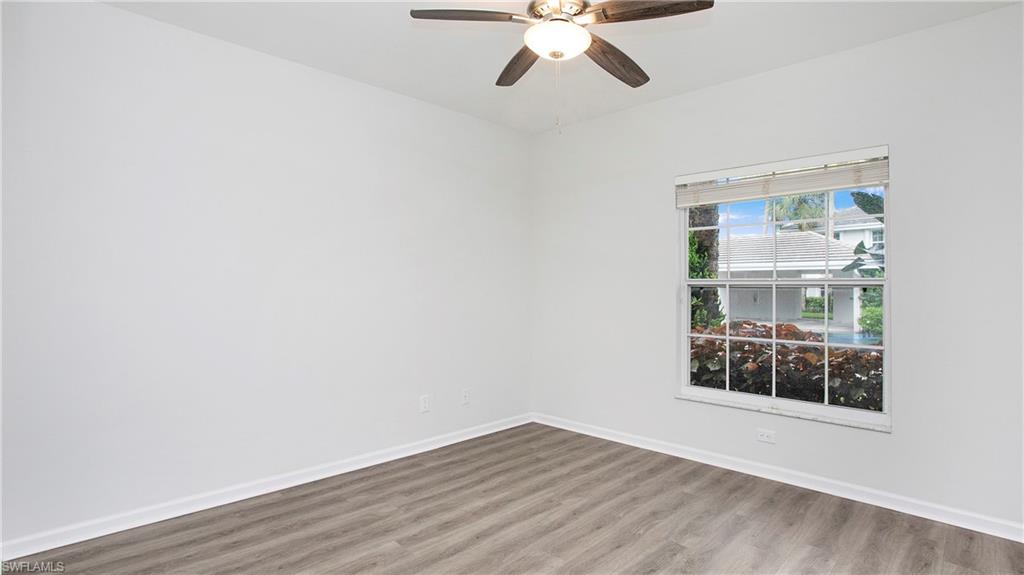 6225 Bellerive Avenue, Unit 1501 Naples, FL 34119 - Photo 13 of 22 an empty room with wooden floor fan and windows
